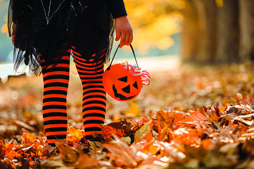 Little girl in witch costume having fun outdoors on Halloween trick or treat